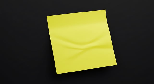 A yellow sticky note on a black surface photo