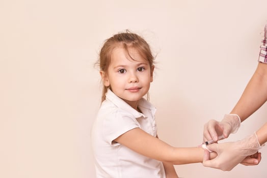 Young caucasian female child receiving vaccine injection with healthcare professional in gloves. photo