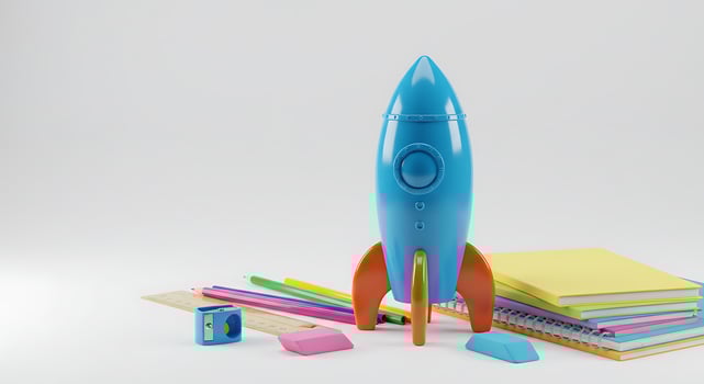 A toy rocket sitting next to a stack of school supplies photo