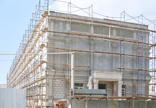 Large concrete building under construction with scaffolding and blue sky in background. photo