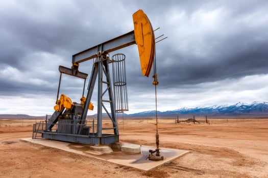 Pump jack extracting crude oil on a cloudy day with snowy mountains in background photo