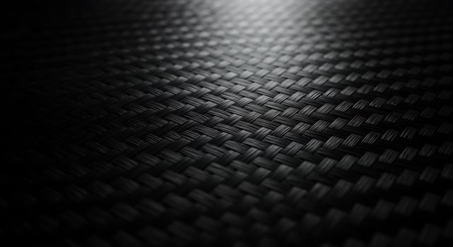 Black carbon fiber background with light shining through photo