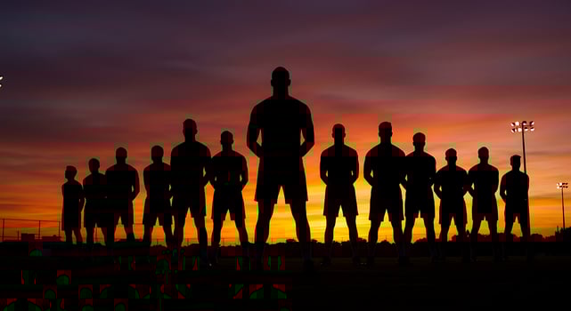 Silhouettes of soccer players standing in front of a sunset photo