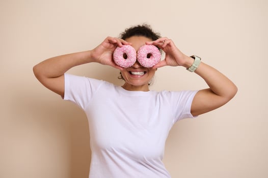 Woman Playfully Holding Two Doughnuts Against Her Eyes with a Cheerful Expression photo
