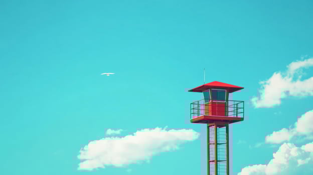 Red Metal Tower Against a Vibrant Blue Sky with Fluffy Clouds photo