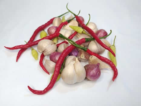 Garlic, onion, and fresh chili arranged in a white background photo