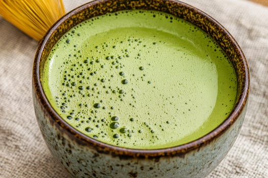Green matcha tea in a ceramic bowl with a whisk nearby. Matcha organic caffeine concept. photo