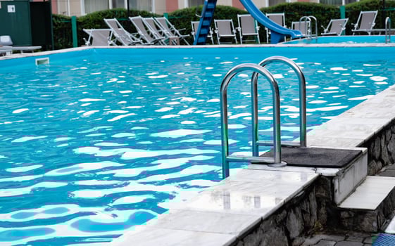 pool with metal ladder and lounge chairs around. photo