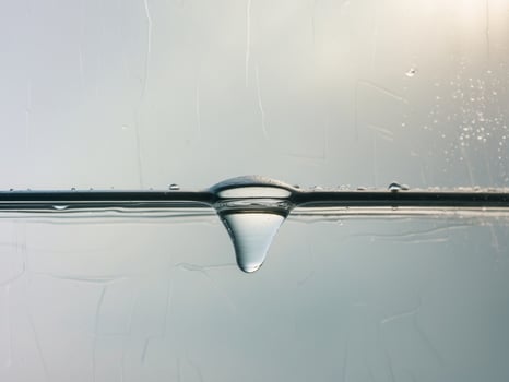 Water droplet on glass surface with sun shining through photo