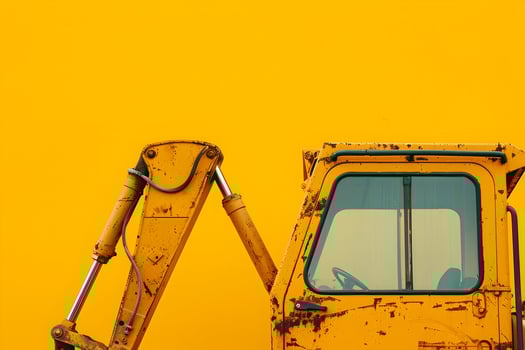A yellow excavator is parked against a yellow background photo