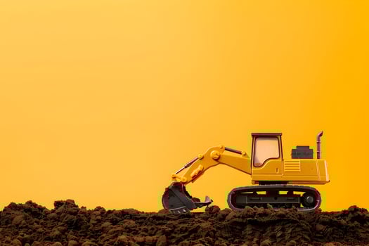 A toy excavator is sitting on top of a mound of dirt photo