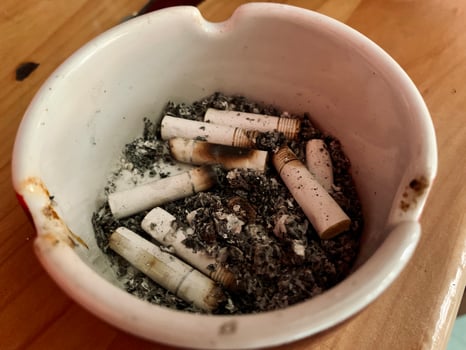 Cigarette ashtray full of cigarette ash on the table photo