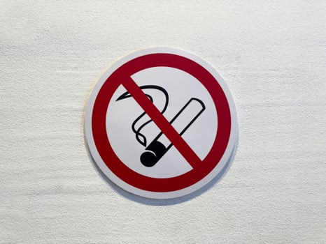 Close up of no smoking sign on white wall. Red circle with cigarette symbol and diagonal line emphasizes public health, safety and clean air in indoor environments photo