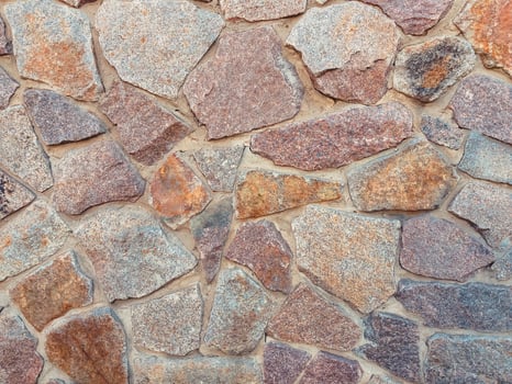 Wall made of stone with a pattern of different colored stones photo
