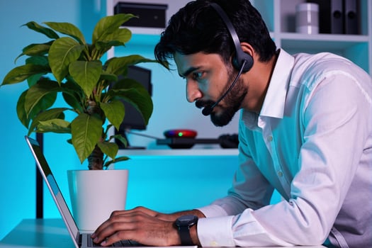 A man wearing a headset on his laptop photo