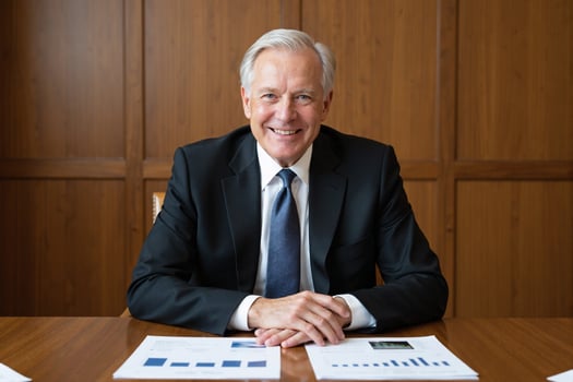 A man in a suit sitting at a table with papers photo