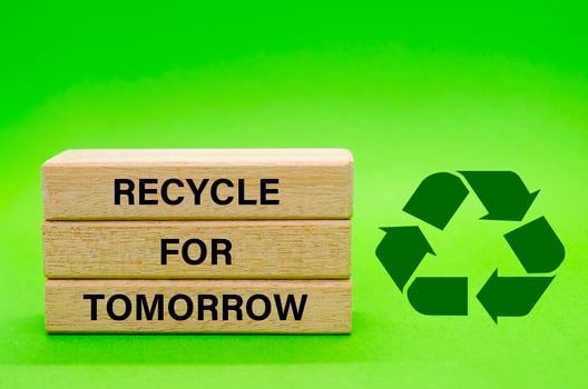 Recycle symbol with wooden blocks with text Recycle For Tomorrow on a green background. Promoting reuse, reduce, and recycle for sustainability. photo