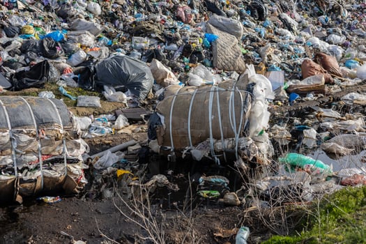 Rubble and trash cover the landfill area, with various types of waste and pollution evident, highlighting recycling challenges photo