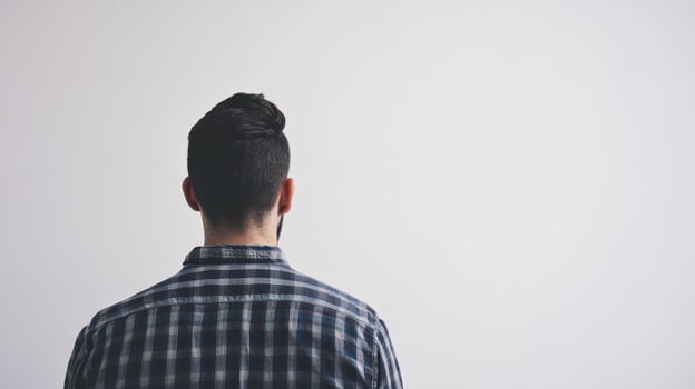 Man in plaid shirt by blank wall indoors photo
