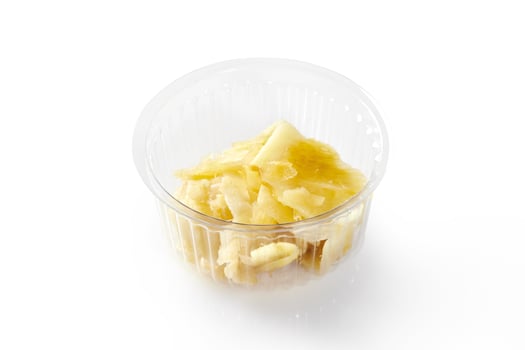 Pickled ginger slices in plastic container on white background photo