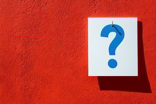 Big blue question mark hanging on a red wall photo
