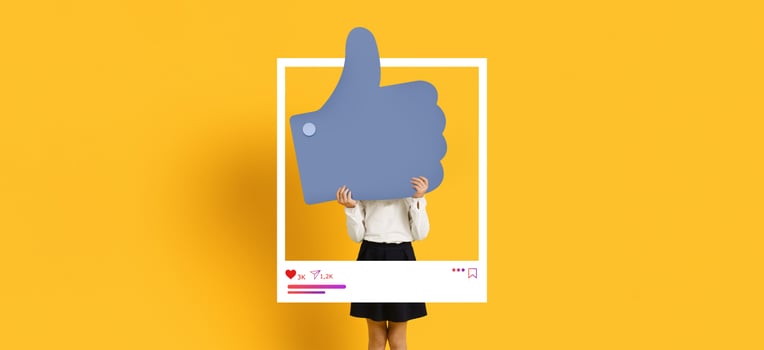 A person stands behind a large thumb up symbol, signifying approval and engagement on social media. photo