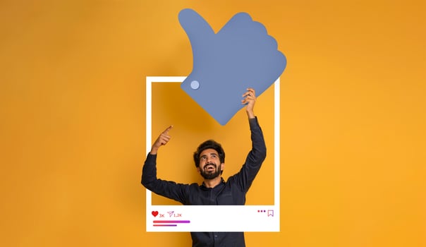 A man stands against a vibrant yellow background, celebrating a thumbs-up gesture. He points upwards, embodying enthusiasm for social media engagement and positive content creation. photo