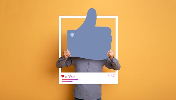 A person holds a large thumbs up symbol in a bright yellow background, symbolizing approval and social media interaction. photo
