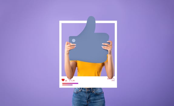A person is holding a large thumbs up symbol in front of a bright purple background. They wear a casual outfit, exuding a positive vibe that resonates with online influencers and bloggers. photo
