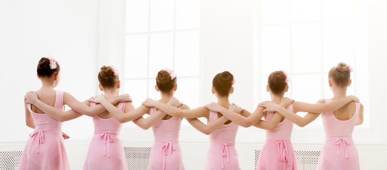 Young girls dancing ballet in studio. Choreographed dance by a group of graceful pretty young ballerinas practicing during class before performance. Classical dance school photo