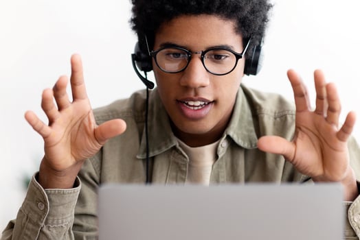 Online education concept. African American teen student in headphones watching webinar, taking part in web conference or distance lesson on laptop computer. Black teenager studying remotely from home photo