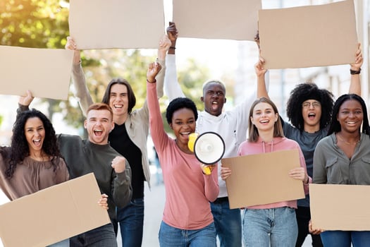 Black motivated lady with loudspeaker leading international group of strikers, demonstrators yelling slogans and holding empty placards, walking by street. Strike, demonstration, protest concept photo