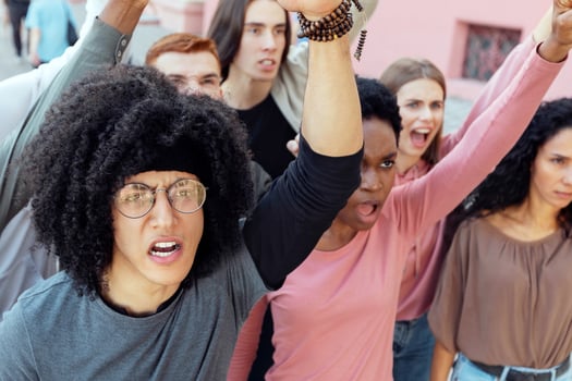 Top view of international group of demonstrators making strike on the street, yelling slogans and raising fist up, closeup. Multiracial millennial men and women protesting against government politics photo
