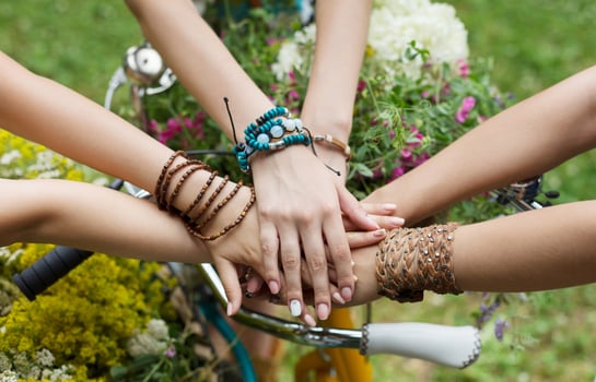 United hands of young females. Stylish girlfriends in boho hippie bracelets near bicycle handlebar, top view. Togetherness and support, youth fashion and active lesiure. Women friendship photo