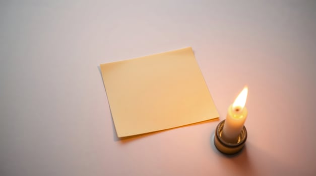 A high-angle shot of a sticky note lit by candlelight, with gentle flickering light and a warm glow. photo