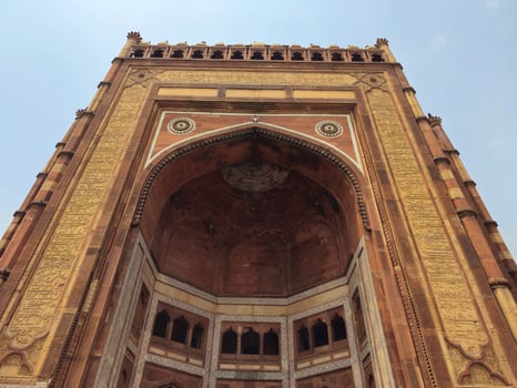 A towering red sandstone gateway with intricate Mughal architecture and inscriptions. This is the Buland Darwaza, the grand entrance to Fatehpur Sikri, a historical city photo
