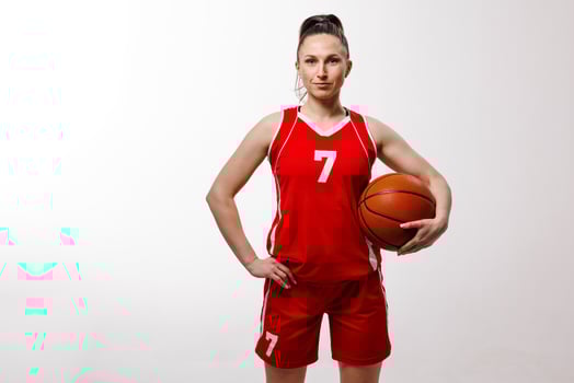 Confident female basketball player in red uniform posing with ball on white background, showing strength and determination in professional sports portrait. photo