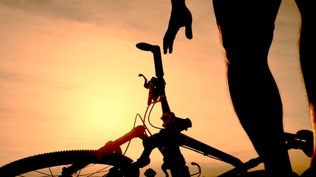 A person standing next to a bike at sunset photo