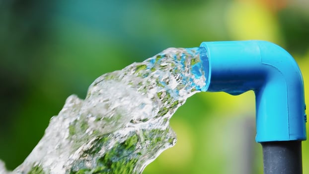 A blue water pipe is pouring water into a green background photo