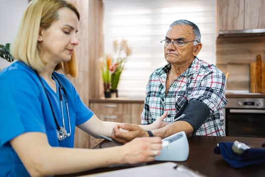 Doc checks elderly man's blood pressure photo