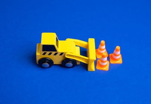 A yellow bulldozer moves traffic cones. The concept of establishing or removing restrictions. Implementing new rules. Construction zones. Policy adjustments, and public safety measures. photo