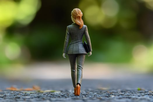 Businesswoman figurine walking away on a path, carrying a briefcase photo