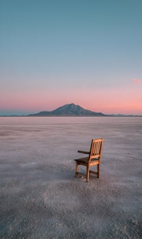 Wooden chair stands alone on a vast salt flat at sunrise offering quiet contemplation and solitude photo