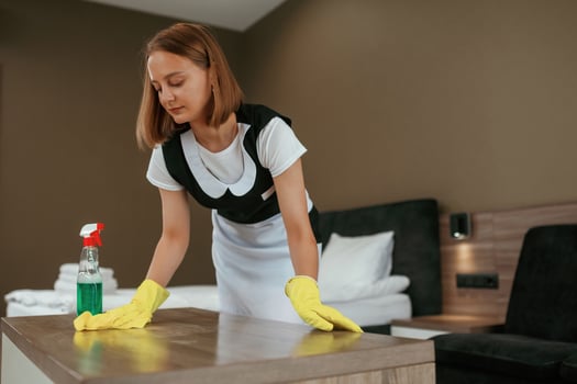Cleaning the table. Young chambermaid is in hotel room, photo