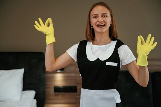 Cleaning is finished, in yellow gloves,. Young chambermaid is in hotel room photo