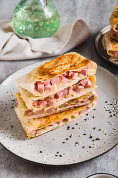 Crispy envelopes with sausage and cheese in flat bread on a plate on the table vertical view photo
