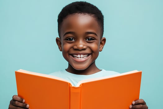 Happy black child smiling and holding an open book on turquoise background photo
