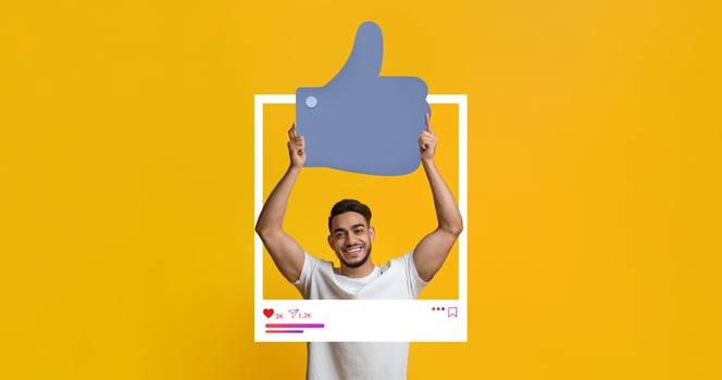 A young man smiles while holding a large thumbs-up symbol in front of a bright yellow backdrop. He interacts with social media content, showcasing a positive vibe that attracts online followers. photo