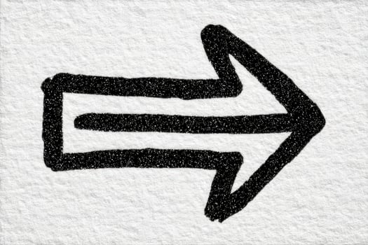 A bold black arrow is drawn on a textured, light background, indicating direction to the right. The arrows simplicity emphasizes clarity and purpose in visual communication. photo