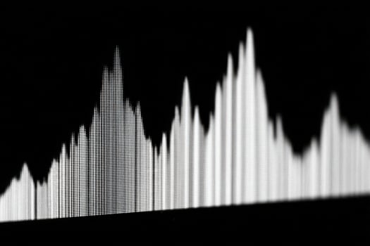 A series of vertical bars rise and fall to represent sound frequencies on a dark background. photo